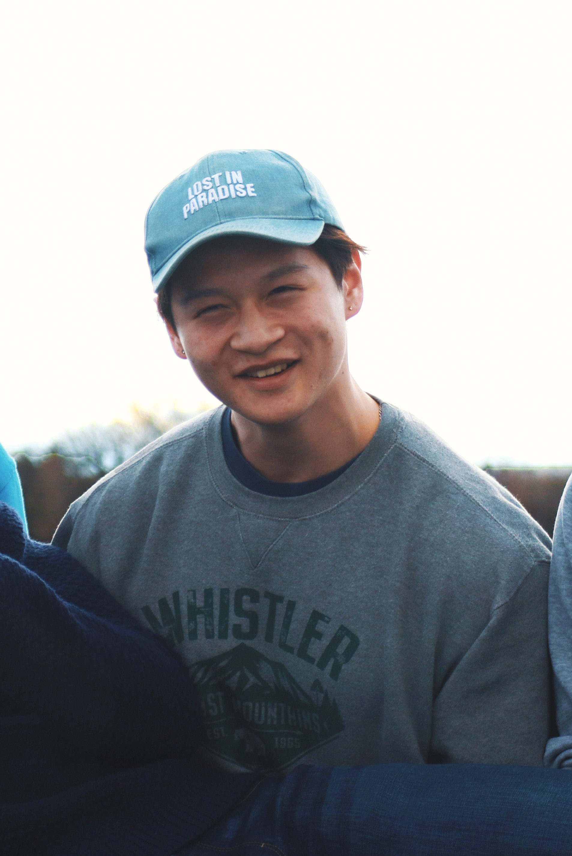 Derek Chu wearing a blue hat with his friends by the pier